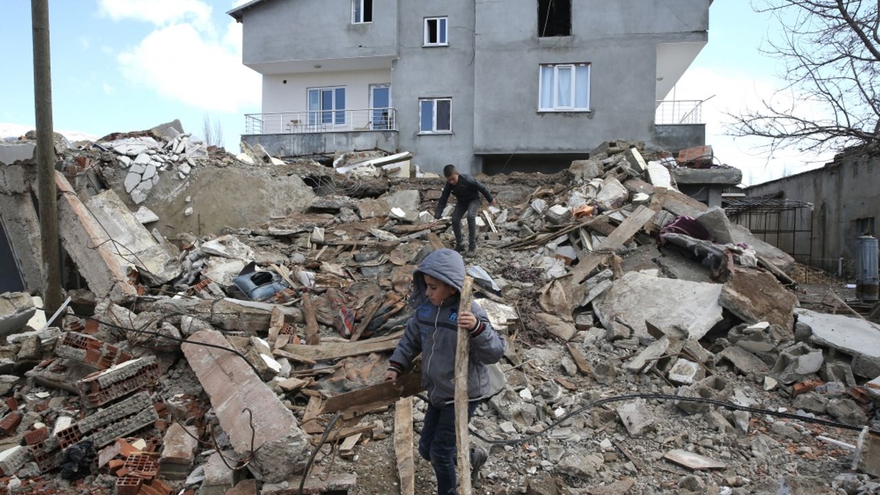 Depremde yıkılan evinin enkazından geriye kalanları çocuklarıyla topluyor